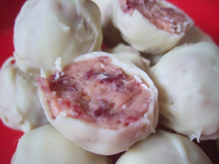 A pile of white chocolate Cosmopolitan truffles with one halved.