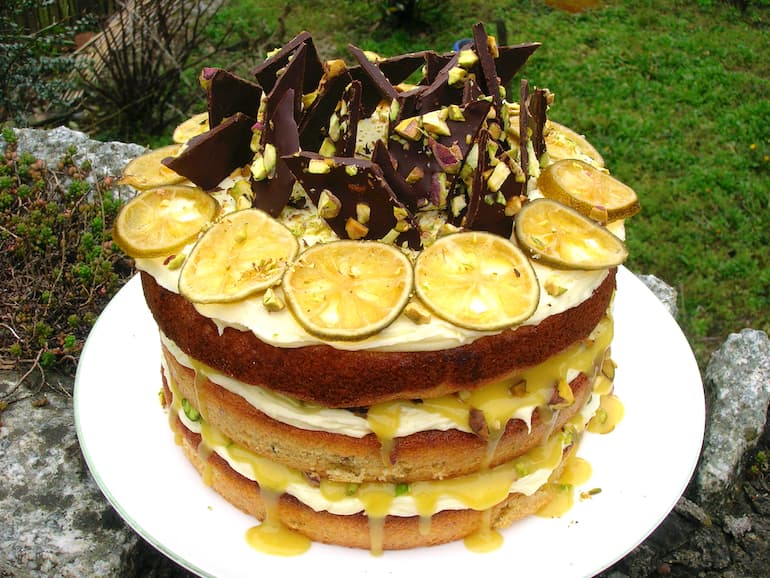 Lime and pistachio cake with chocolate shards and lime slices.