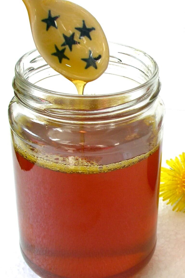 Open jar of dandelion honey (vegan honey) with drizzling spoon.