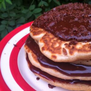 Stack of buckwheat apple and raisin pancakes smothered with chocolate sauce.