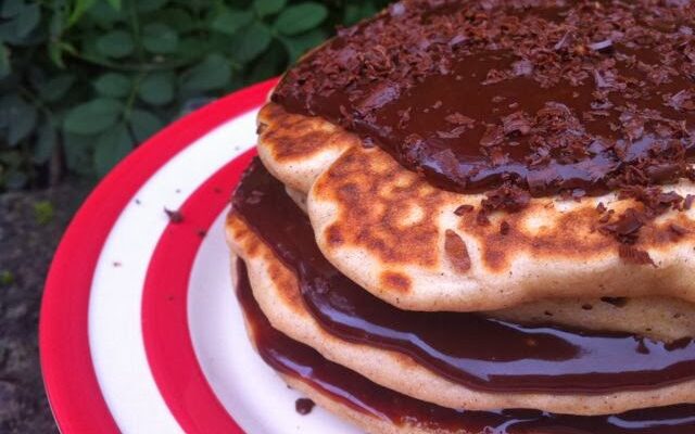 Stack of buckwheat apple and raisin pancakes smothered with chocolate sauce.