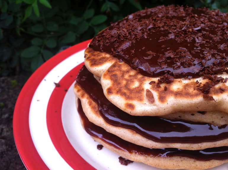 Stack of buckwheat apple and raisin pancakes smothered with chocolate sauce.