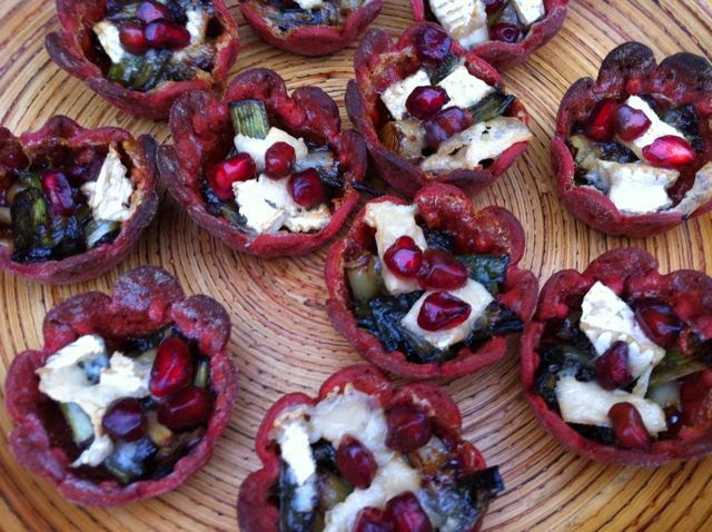 Baby leeks, goat's cheese and pomegranate seeds in beetroot pastry cases.