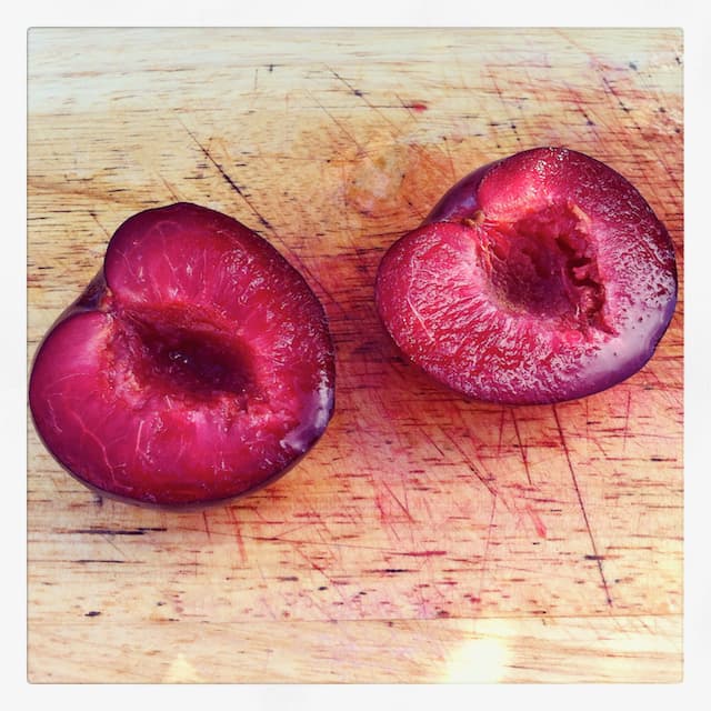 Two purple plum halves with stone removed.