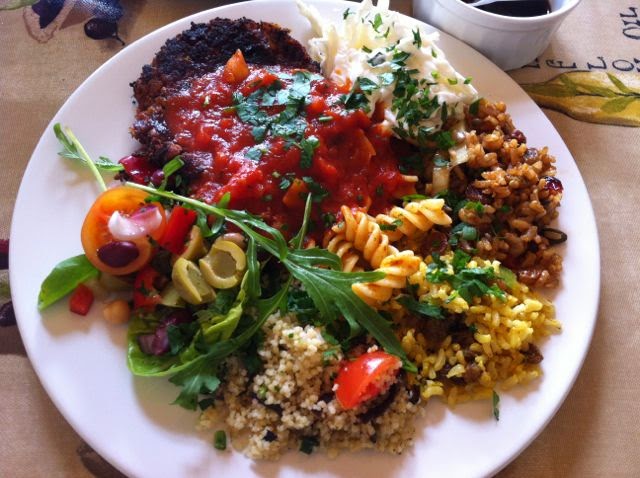 A plate of mixed vegetarian salads and a fritter with tomato sauce.