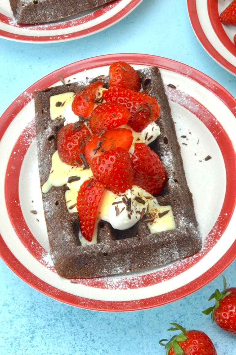 Loaded chocolate cake waffle on red Cornishware plate.