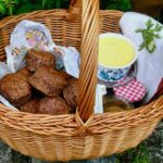 Basket of rich dark chocolate scones with tub of clotted cream.