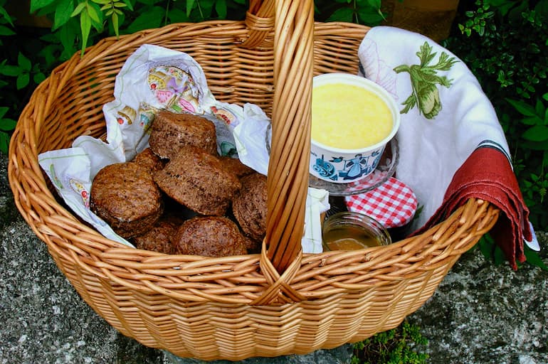 Basket of rich dark chocolate scones with tub of clotted cream.