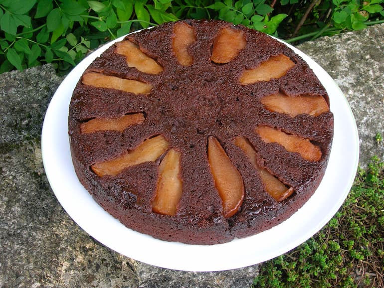 Homemade chocolate pear upside-down cake on white plate.