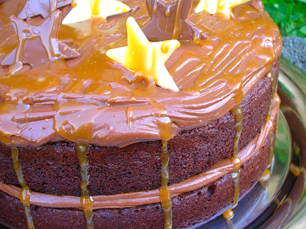 Close up of one side of a salted caramel chocolate cake decorated with white and milk chocolate stars.