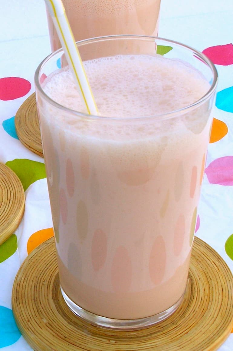 A glass of pink grapefruit sunshine smoothie with straw.