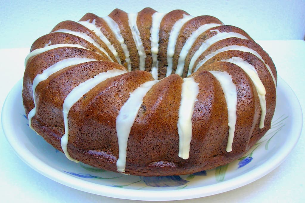 Banana bundt cake with white stripy icing, on a plate