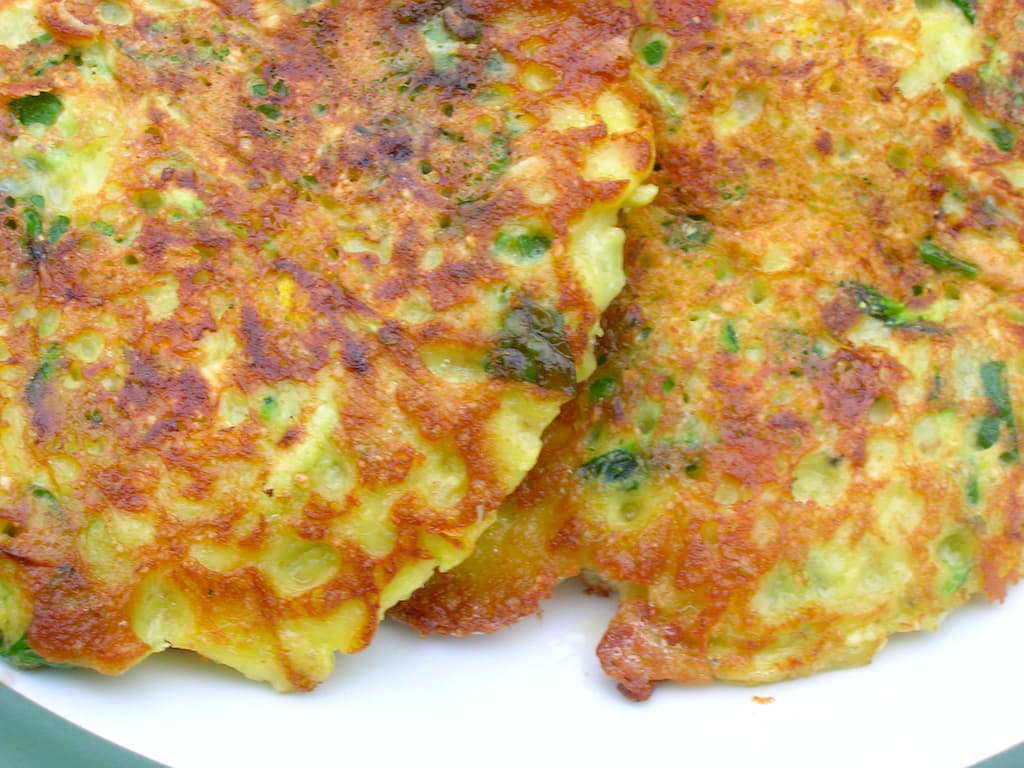 Close up of two spiced courgette fritters on a plate.