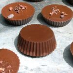 Homemade Peanut Butter Cups laid out on a piece of slate. One is upside down.