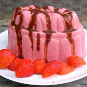 A moulded vegetarian strawberry blancmange topped with chocolate balsamic and strawberries around the bottom.