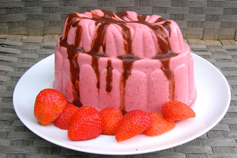 A moulded vegetarian strawberry blancmange topped with chocolate balsamic and strawberries around the bottom.