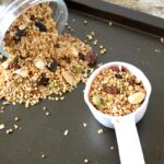 Scoop of gorgeous gluten-free granola with some spilling out of jar.