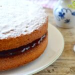 Partial view of wholemeal Victoria sponge cake on plate