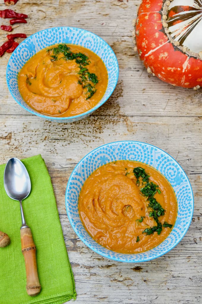 Two blue bowls of orange sweet potato and carrot soup.