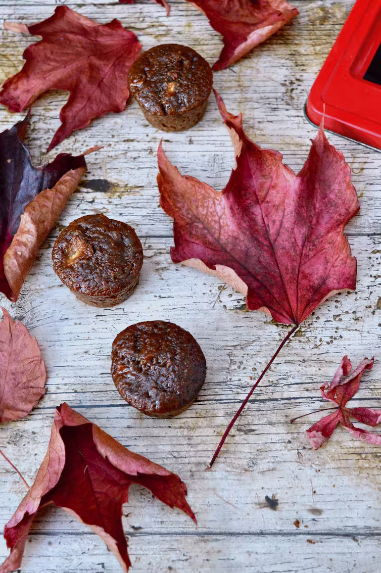 Sticky ginger apple cakes on table amongst autumn leaves.