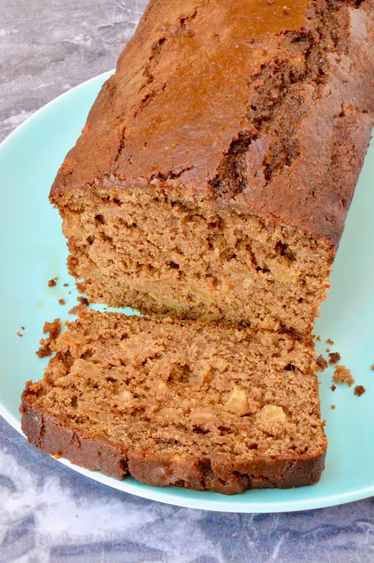 Gingerbread apple loaf on plate, partially sliced.