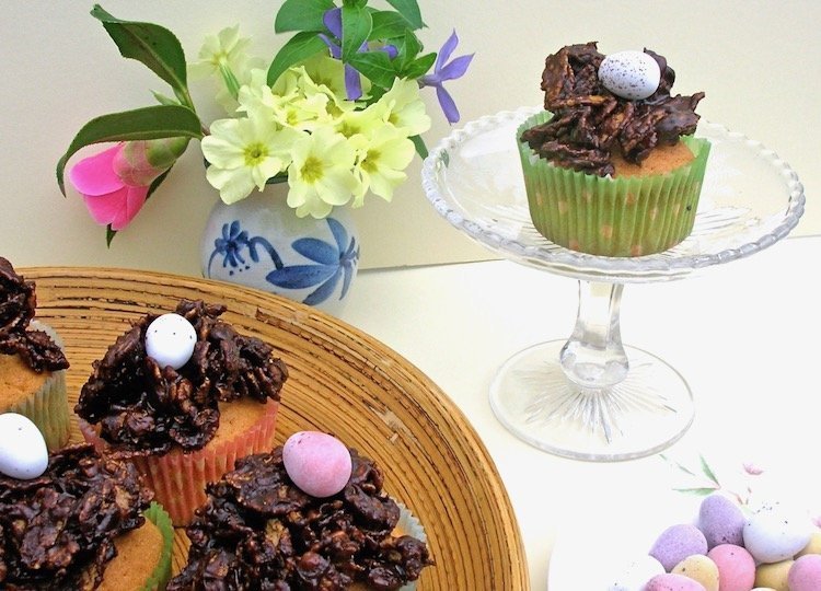 Easter Nest Cupcakes with a plate of mini eggs and a vase of primroses.