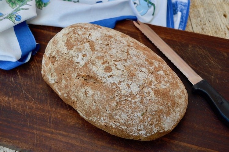 Loaf of Rye Sourdough Bread on bread board with knife.