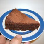 Slice of gluten-free chocolate almond cake on a Cornishware plate.