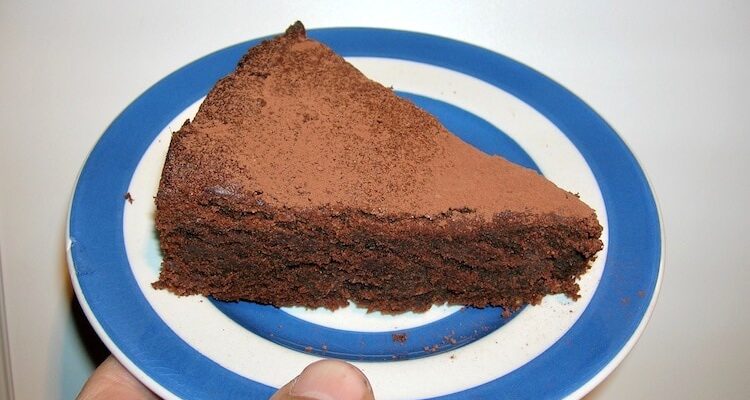 Slice of gluten-free chocolate almond cake on a Cornishware plate.