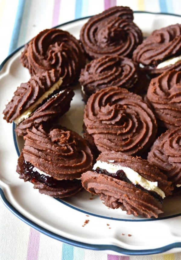 Plate of chocolate Viennese whirls sandwiched with blackcurrant jam and vanilla buttercream.