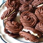 Plate of chocolate Viennese whirls sandwiched with blackcurrant jam and vanilla buttercream.