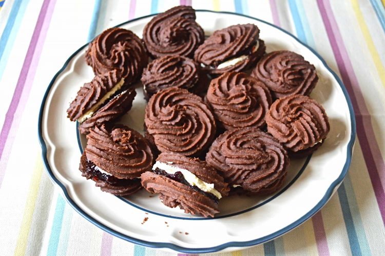 Plate of chocolate Viennese whirls sandwiched with blackcurrant jam and vanilla buttercream.