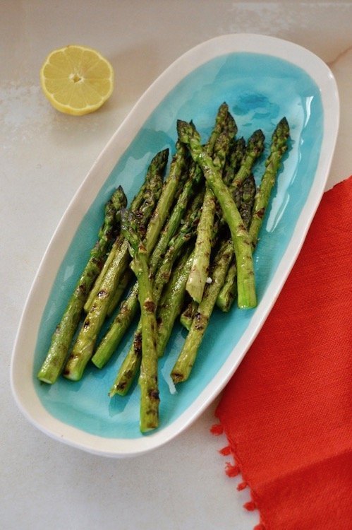 Griddled asparagus on a turquoise serving platter.