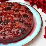 Partial view of a lush purple plum upside-down cake on blue plate.