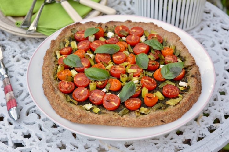 Tomato galette with onion on a plate on the garden table.
