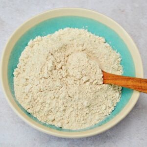 Wholemeal spelt flour in a bowl with wooden spoon.
