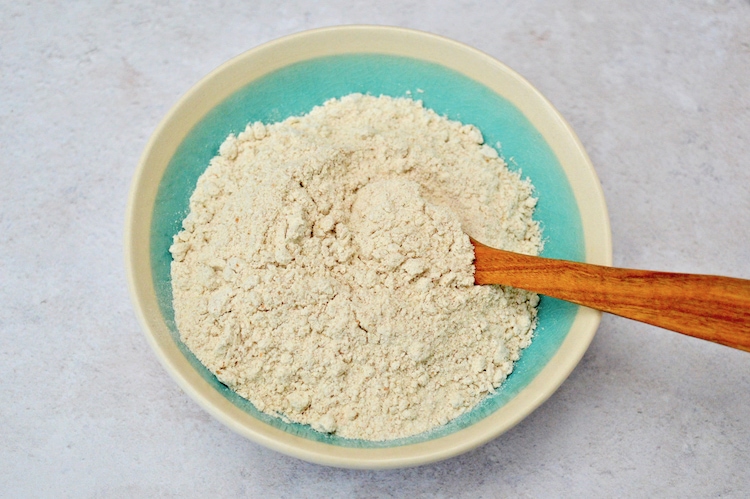 Wholemeal spelt flour in a bowl with wooden spoon.