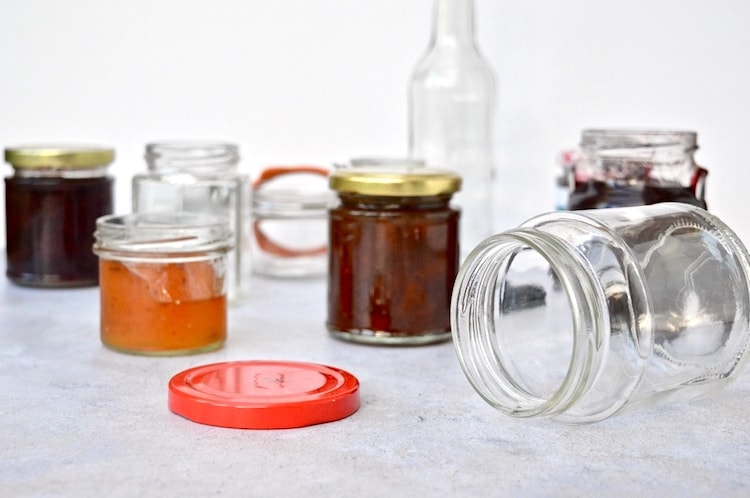 An array of glass jars, both full and empty, to illustrate how to sterilise glass jars.