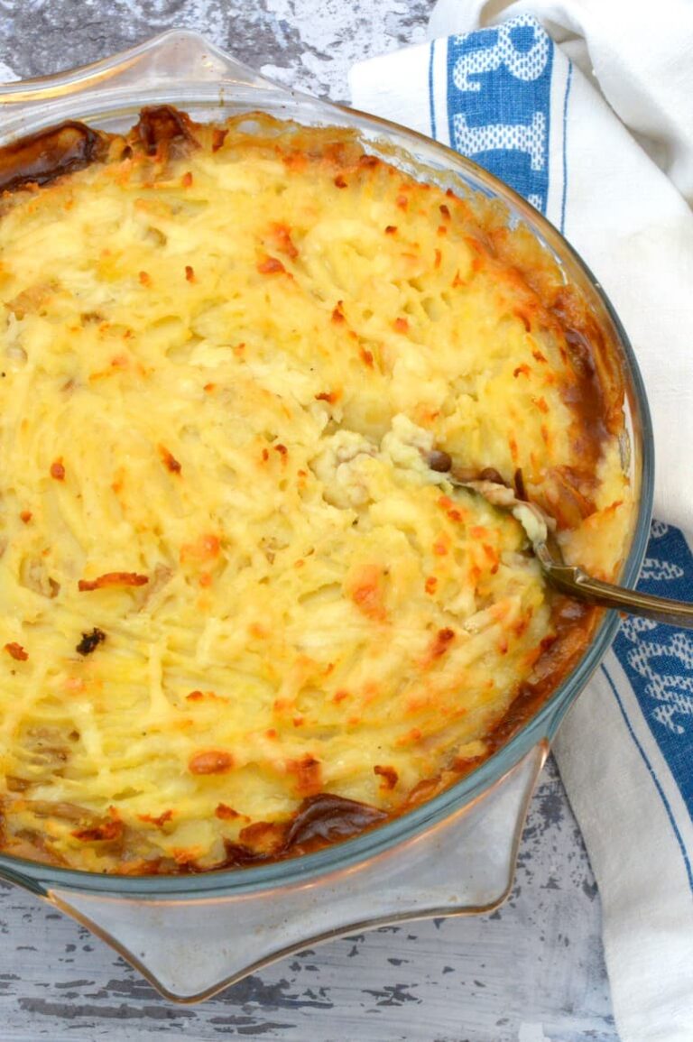 Vegetarian lentil shepherd's pie just out of oven with serving spoon inserted.