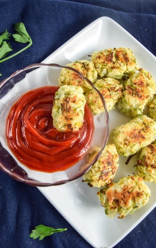 Baked sprout tater tots with a bowl of tomato sauce for dipping.