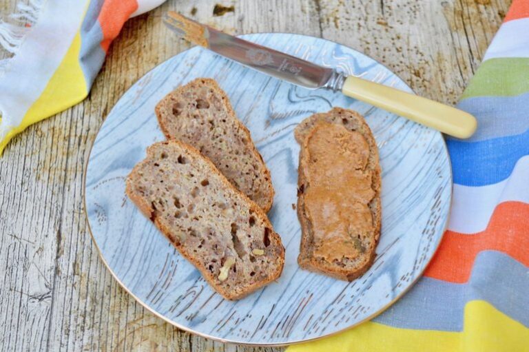 Slices of breakfast banana bread. One spread with homemade peanut butter.
