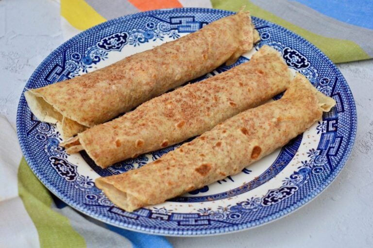 Three rolled chocolate, honey and cream pancakes on a plate.