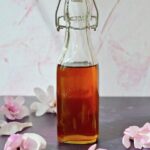 Bottle of Magnolia Syrup with magnolia blossoms.