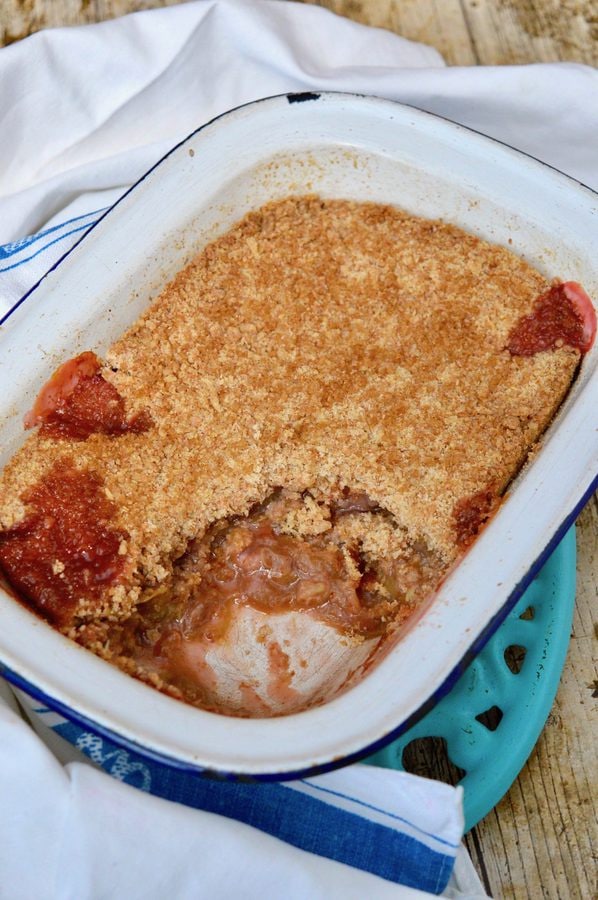Classic rhubarb crumble in baking dish with some removed.