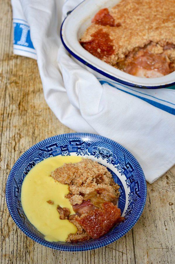 A bowl of homemade rhubarb crumble with custard.