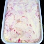 Tub of rhubarb ripple ice cream with white chocolate & rose.