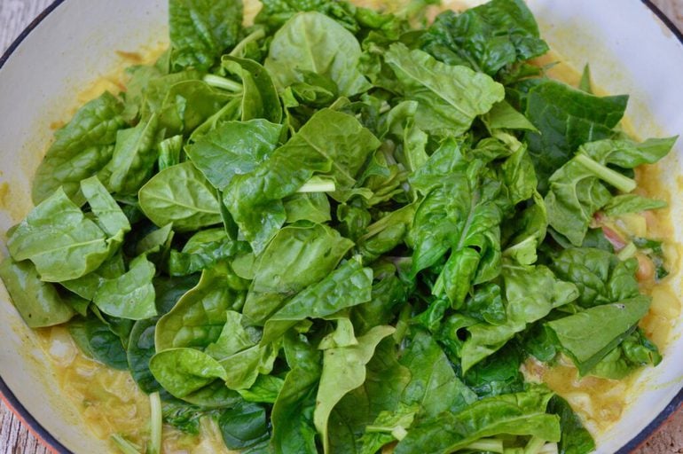 Spinach leaves added to the pan.