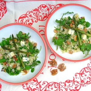 Two bowls of quinoa salad with watercress, walnuts, blue cheese and roasted asparagus.