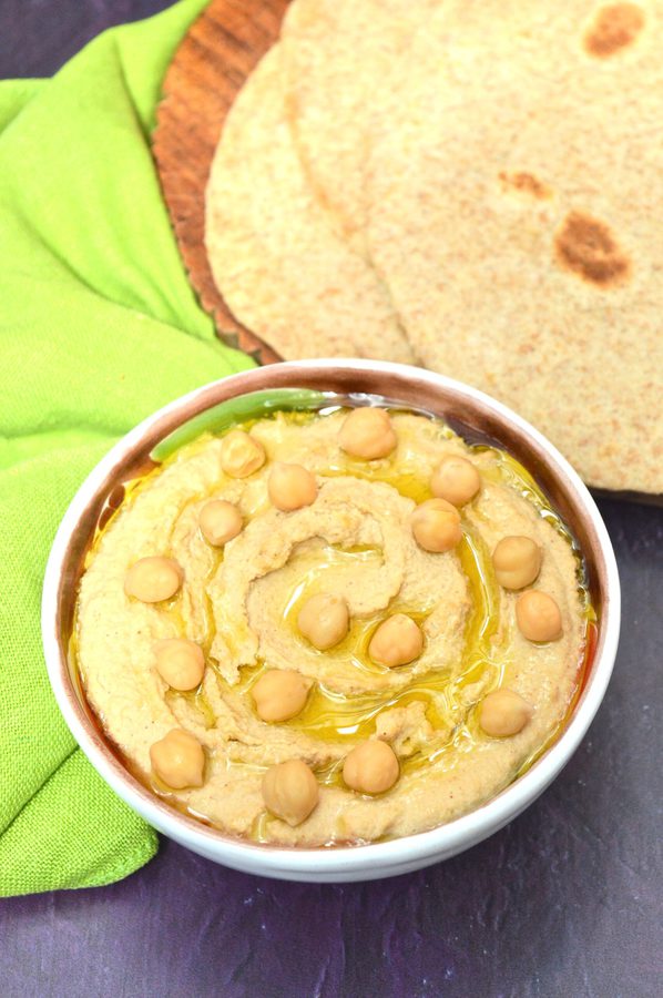 A bowl of traditional hummus bi tahini with flatbreads.