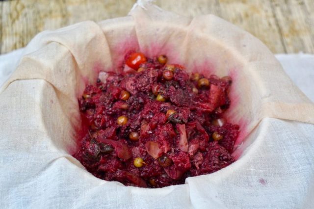 Cooked foraged fruit being strained through a muslin cloth in order to make hedgerow jelly.